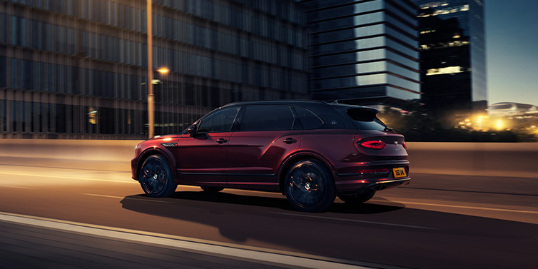 Bentley Perth Bentley Bentayga Extended Wheelbase Mulliner SUV in Cricket Ball red paint driving dynamically in city at night