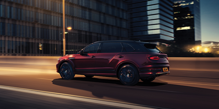Bentley Perth Bentley Bentayga Extended Wheelbase Mulliner SUV in Cricket Ball red paint driving dynamically in city at night