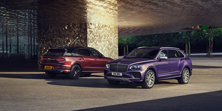 Bentley Perth A duo of Bentley Bentayga Extended Wheelbase Mulliner SUVs parked in a city environment, with Tanzanite Purple and Cricket Ball red exterior paint